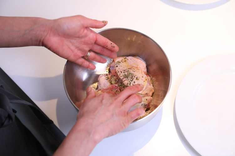 加熱した鶏肉にオリーブオイル、塩コショウをなじませている写真